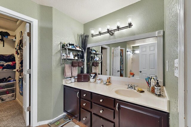 7720 Red Finch Ct NW, Albuquerque, NM 87114 - bathroom featuring a textured wall, a spacious closet, vanity, and a shower