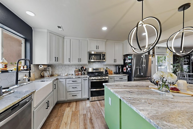 7720 Red Finch Ct NW, Albuquerque, NM 87114 - kitchen featuring appliances with stainless steel finishes, light wood finished floors, recessed lighting, tasteful backsplash, and decorative light fixtures