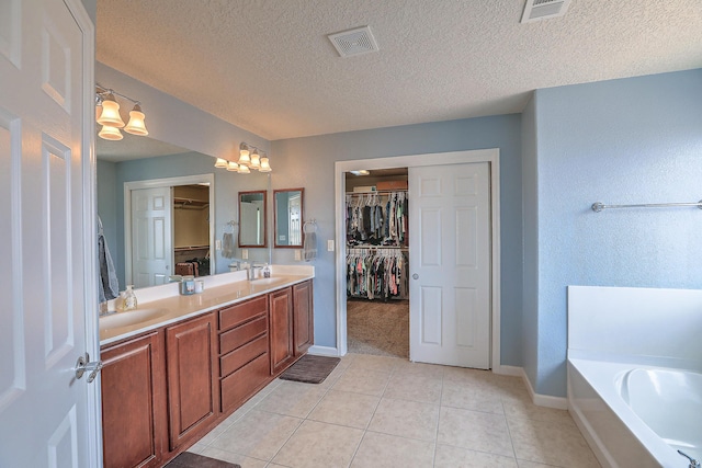 3929 Las Colinas Ave, Rio Rancho, NM 87124 - bathroom featuring a textured ceiling, baseboards, tile patterned flooring, double vanity, and a bath