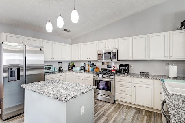 6605 Country Knoll Ct NW, Albuquerque, NM 87114 - kitchen with stainless steel appliances, a textured ceiling, vaulted ceiling, a kitchen island, and light wood-style flooring