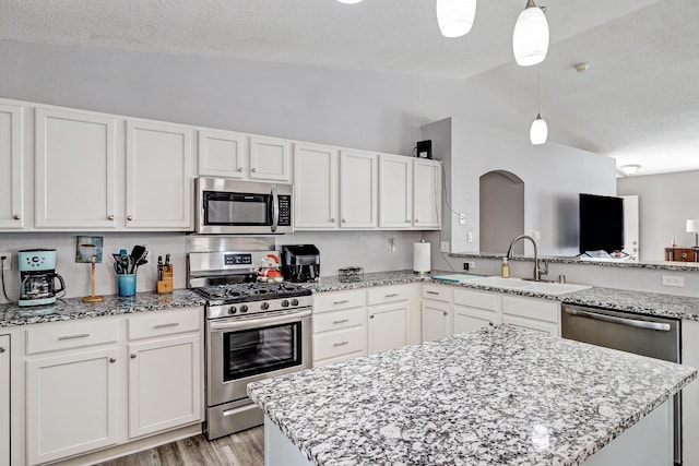 6605 Country Knoll Ct NW, Albuquerque, NM 87114 - kitchen with stainless steel appliances, vaulted ceiling, a sink, white cabinetry, and a textured ceiling