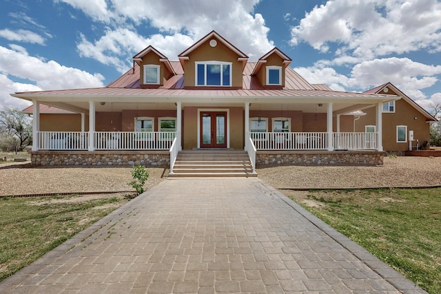 farmhouse inspired home with stucco siding, covered porch, a standing seam roof, and metal roof