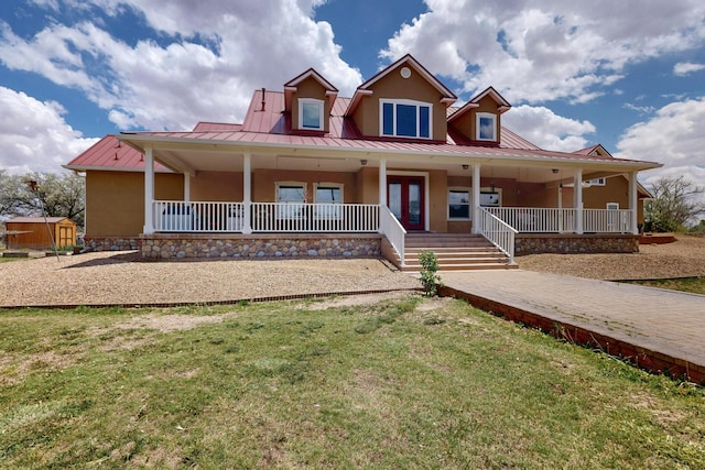 view of front facade with stucco siding, a front yard, a standing seam roof, and a porch