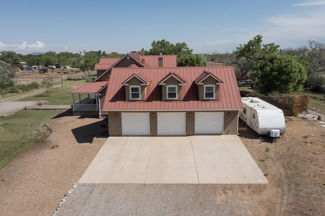 view of front of property featuring driveway, a garage, stucco siding, and metal roof