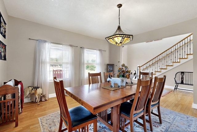 dining space featuring light wood finished floors, baseboards, and stairs