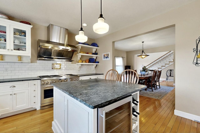 kitchen with high end stainless steel range, extractor fan, beverage cooler, open shelves, and tasteful backsplash
