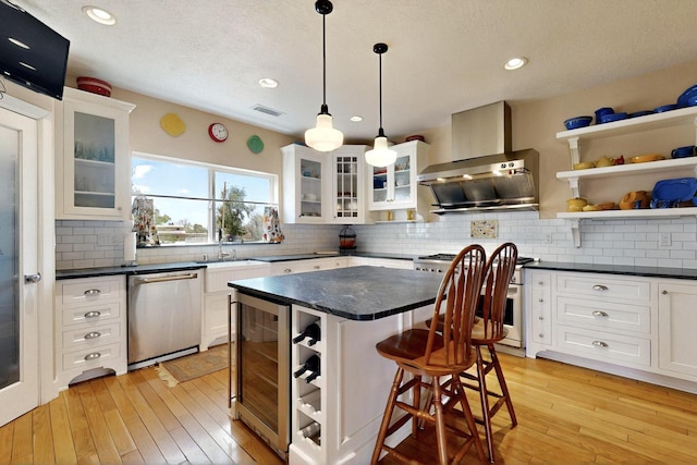 kitchen with stainless steel appliances, a sink, wine cooler, a kitchen bar, and backsplash