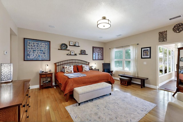 bedroom featuring light wood-style floors, baseboards, and access to outside