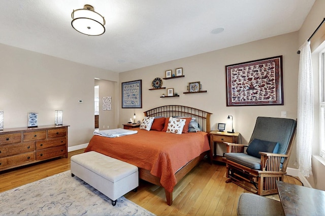 bedroom with wood-type flooring, multiple windows, and baseboards