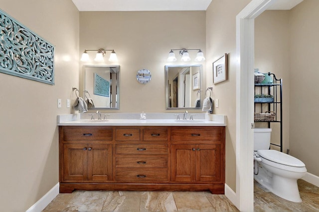 full bathroom featuring toilet, baseboards, and double vanity