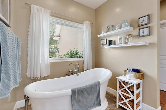 full bathroom featuring a freestanding tub and baseboards