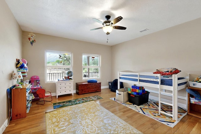 bedroom featuring wood finished floors, baseboards, a ceiling fan, and a textured ceiling