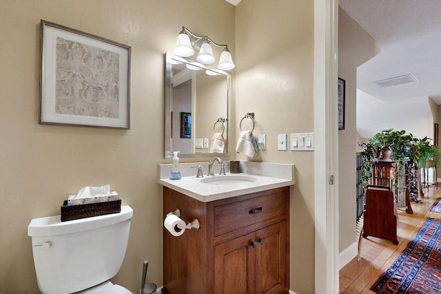bathroom with wood finished floors, vanity, toilet, and baseboards