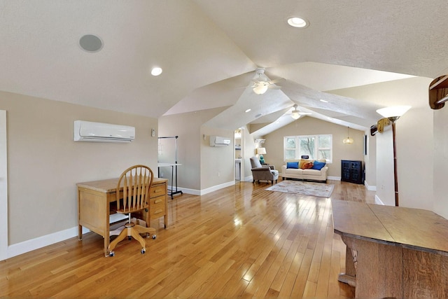 home office featuring a wall unit AC, ceiling fan, vaulted ceiling, light wood-type flooring, and baseboards