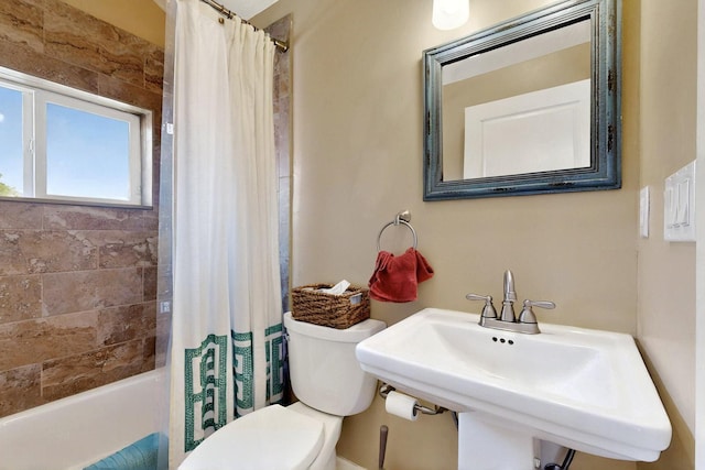 bathroom featuring toilet, a sink, and shower / tub combo