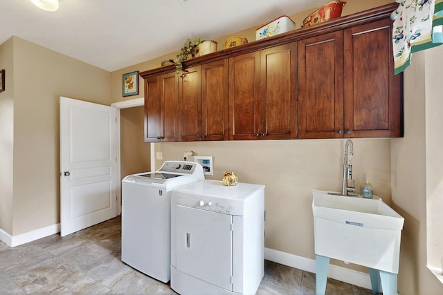 clothes washing area featuring washing machine and clothes dryer, cabinet space, and baseboards