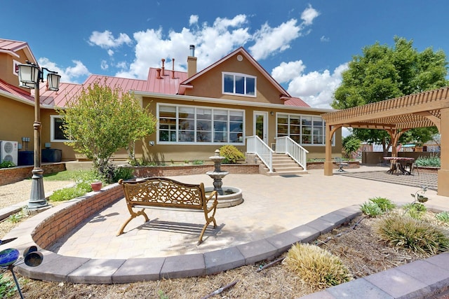 back of property with stucco siding, metal roof, a standing seam roof, and a pergola