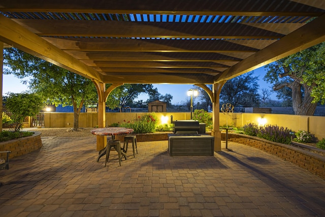 70 Sanchez Rd, Belen, NM 87002 - patio terrace at dusk with a storage unit, an outdoor structure, outdoor dining area, a pergola, and a fenced backyard
