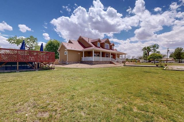 back of house featuring covered porch, a lawn, and metal roof