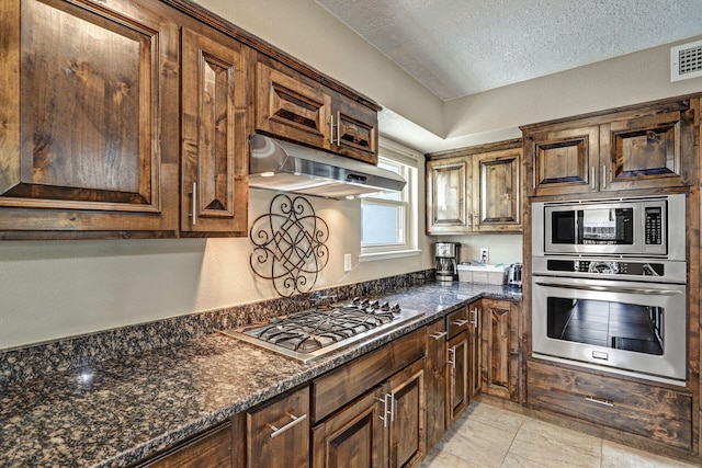6400 Torreon Dr NE, Albuquerque, NM 87109 - kitchen featuring appliances with stainless steel finishes, under cabinet range hood, a textured ceiling, and dark stone countertops
