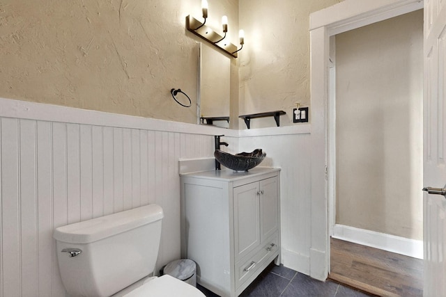 608 Coal Ave SE, Albuquerque, NM 87102 - bathroom featuring toilet, wainscoting, vanity, a textured wall, and tile patterned floors
