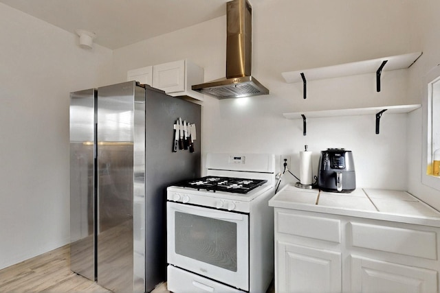 608 Coal Ave SE, Albuquerque, NM 87102 - kitchen with gas range gas stove, open shelves, wall chimney range hood, tile counters, and white cabinetry