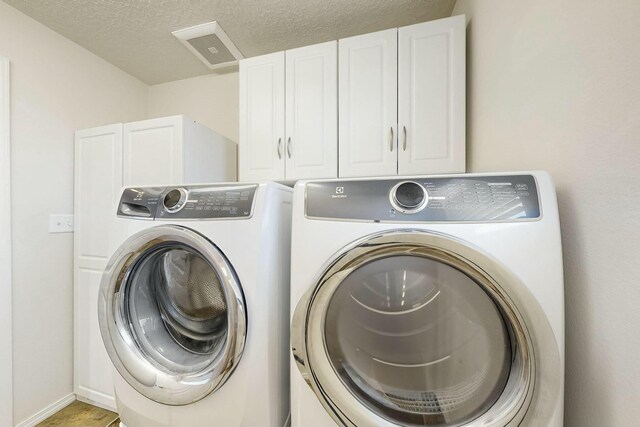9631 Iron Rock Dr NW, Albuquerque, NM 87114 - laundry area with washer and clothes dryer, cabinet space, and a textured ceiling