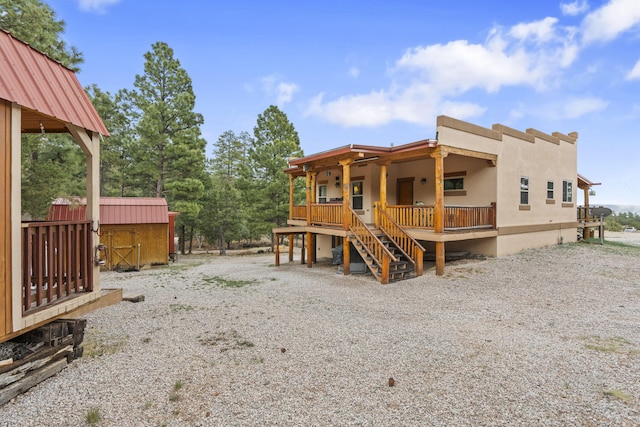 160 Black Bear Rd, Ramah, NM 87321 - back of property with a storage unit, covered porch, stucco siding, and stairs