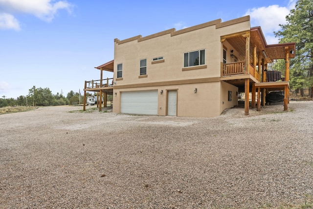 160 Black Bear Rd, Ramah, NM 87321 - back of property featuring an attached garage, driveway, stucco siding, and a wooden deck