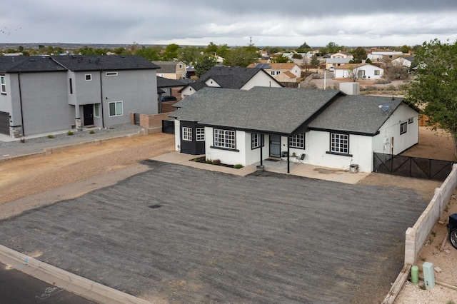 404 Pecos Loop SE, Rio Rancho, NM 87124 - view of front facade featuring a residential view, roof with shingles, a gate, and stucco siding