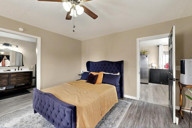 404 Pecos Loop SE, Rio Rancho, NM 87124 - bedroom with wood finished floors, stainless steel refrigerator, baseboards, ensuite bathroom, and ceiling fan