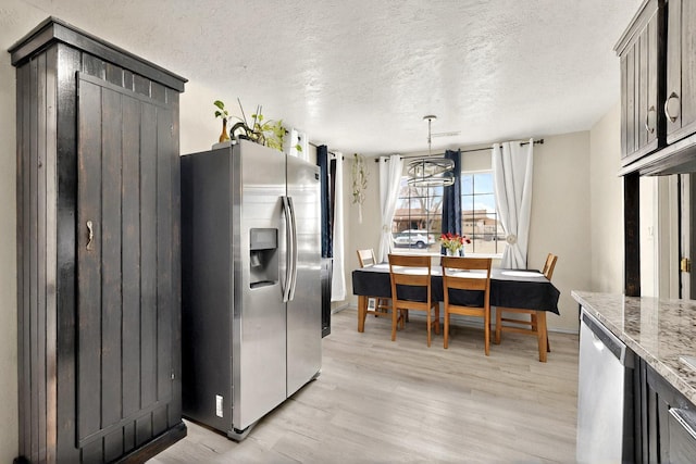 404 Pecos Loop SE, Rio Rancho, NM 87124 - kitchen featuring appliances with stainless steel finishes, light wood finished floors, a textured ceiling, light stone countertops, and decorative light fixtures