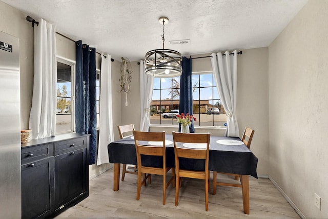 404 Pecos Loop SE, Rio Rancho, NM 87124 - dining room featuring a textured ceiling, light wood-style flooring, a chandelier, and baseboards