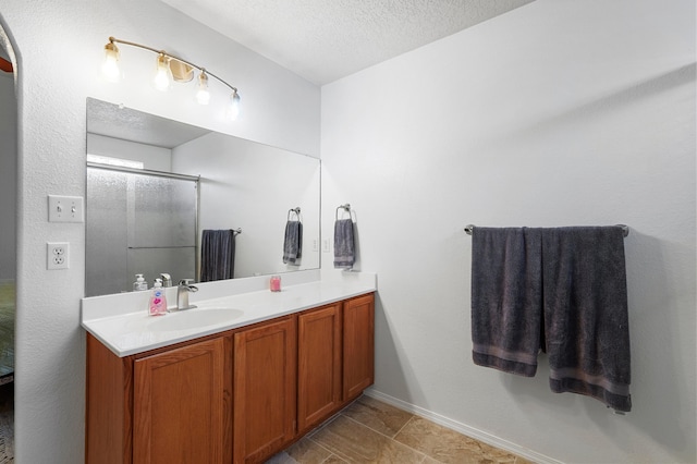 3772 Havasu Falls St NE, Rio Rancho, NM 87144 - bathroom with vanity, a textured ceiling, a shower with shower door, and baseboards