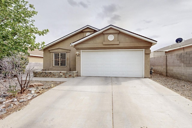 8912 Silverado Ave SW, Albuquerque, NM 87121 - view of front facade featuring stucco siding, concrete driveway, fence, and a garage