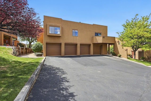view of front of property with stucco siding, an attached garage, and asphalt driveway