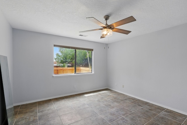 tiled empty room featuring ceiling fan, a textured ceiling, and baseboards