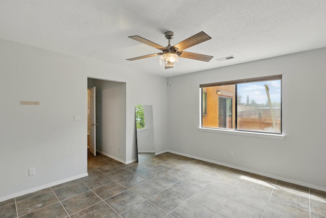 tiled empty room featuring a ceiling fan, a textured ceiling, and baseboards