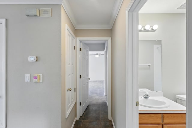 hall featuring a sink, ornamental molding, and dark tile patterned floors