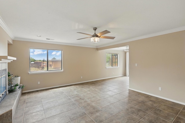 unfurnished living room with ornamental molding, a ceiling fan, plenty of natural light, a tiled fireplace, and tile patterned floors