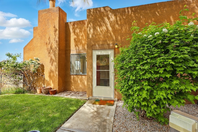 doorway to property with stucco siding and a lawn