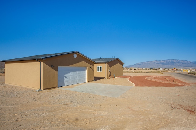 1899 Vargas Rd SE, Rio Rancho, NM 87124 - view of side of property with concrete driveway, an attached garage, a mountain view, and stucco siding
