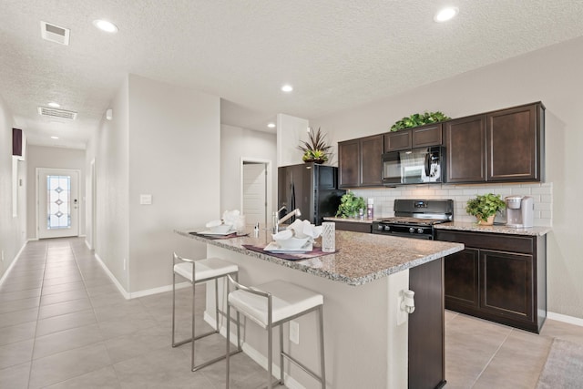 kitchen featuring black appliances, backsplash, light tile patterned floors, a textured ceiling, and dark brown cabinetry