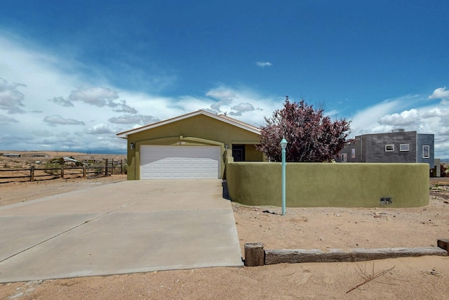 5721 Miller Rd NE, Rio Rancho, NM 87144 - view of front of property featuring fence, an attached garage, stucco siding, and driveway