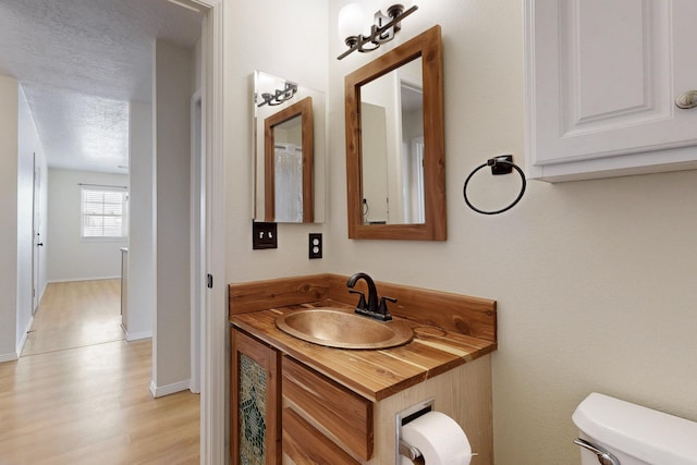 5721 Miller Rd NE, Rio Rancho, NM 87144 - half bathroom with toilet, wood finished floors, vanity, baseboards, and a textured ceiling