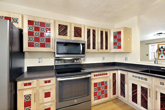 5721 Miller Rd NE, Rio Rancho, NM 87144 - kitchen featuring stainless steel appliances, a textured ceiling, a sink, dark countertops, and light wood-type flooring