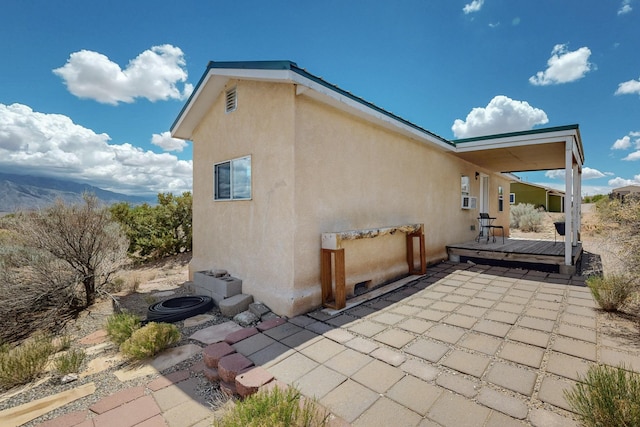 5721 Miller Rd NE, Rio Rancho, NM 87144 - view of side of home featuring a wooden deck, stucco siding, and a patio