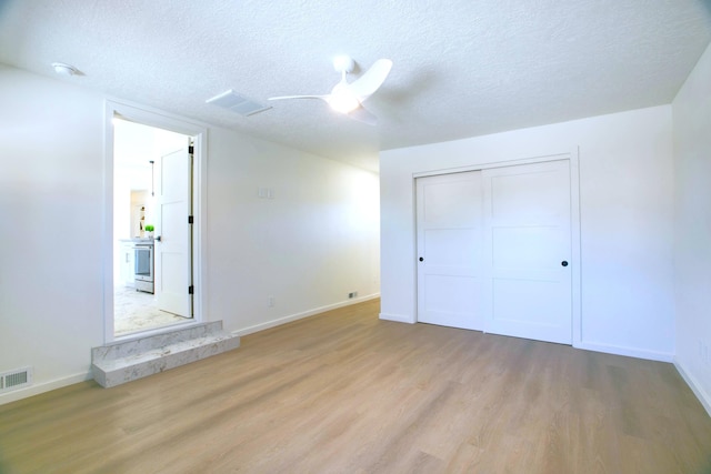 445 Rim Rd, Los Alamos, NM 87544 - unfurnished bedroom featuring light wood-style floors, a textured ceiling, baseboards, a closet, and a ceiling fan