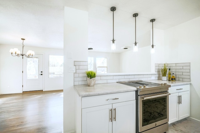 445 Rim Rd, Los Alamos, NM 87544 - kitchen with stainless steel electric range oven, tasteful backsplash, a chandelier, decorative light fixtures, and white cabinetry