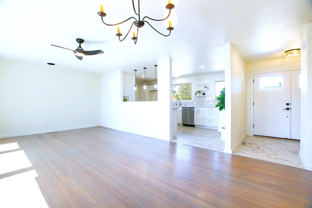 445 Rim Rd, Los Alamos, NM 87544 - unfurnished living room featuring a chandelier, ceiling fan, light wood-type flooring, baseboards, and a sink